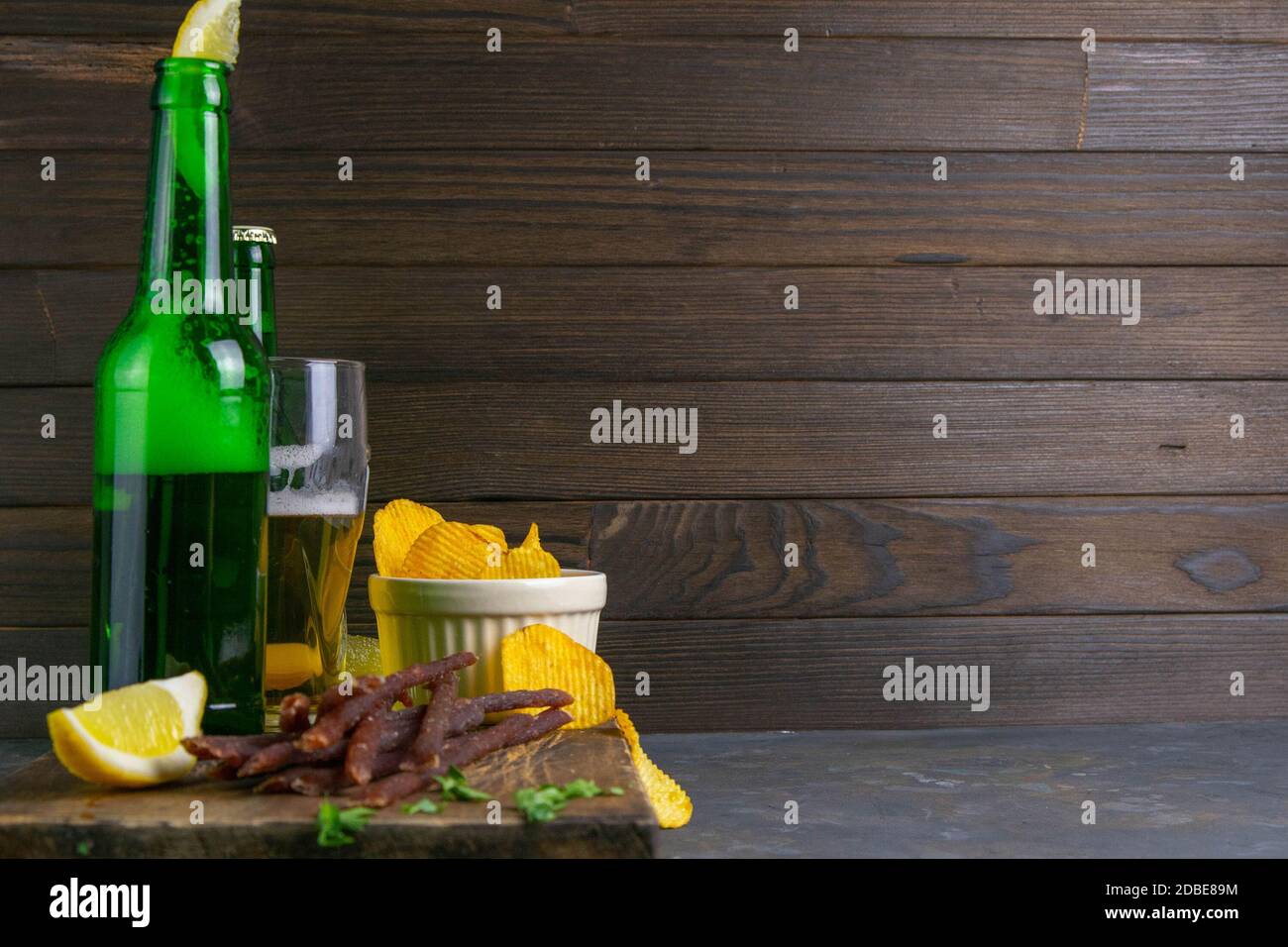 Spuntino al caviale di pesce con birra, limoni e patatine su tavola di legno scuro. Spuntino a base di pesce con birra. Vista frontale con spazio libero. Foto Stock