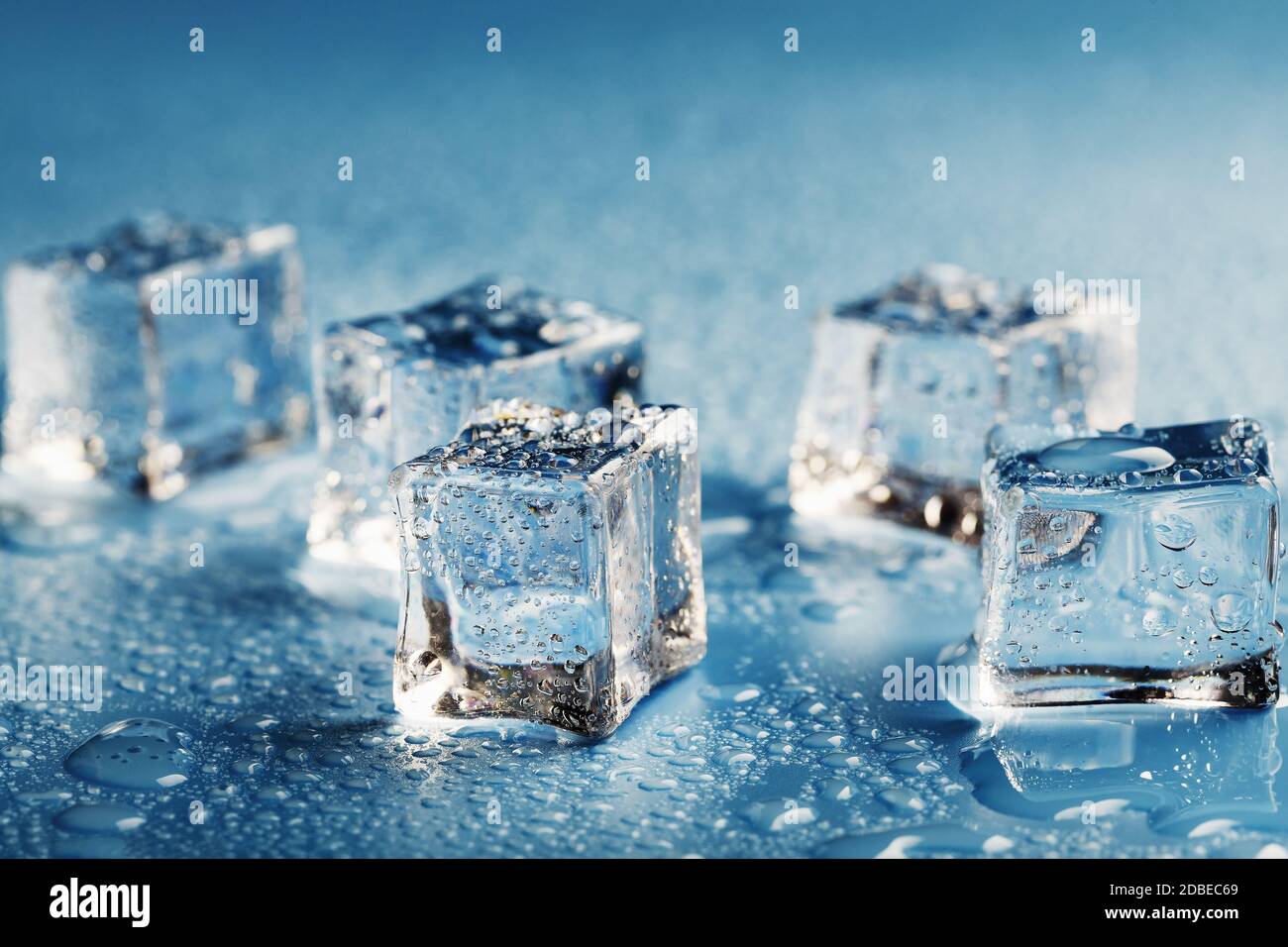 Cubi di ghiaccio ravvicinati con gocce di acqua fusa sparse su sfondo blu.  Macro. Ghiaccio rinfrescante per bevande e cocktail in una giornata calda e  gustosa Foto stock - Alamy