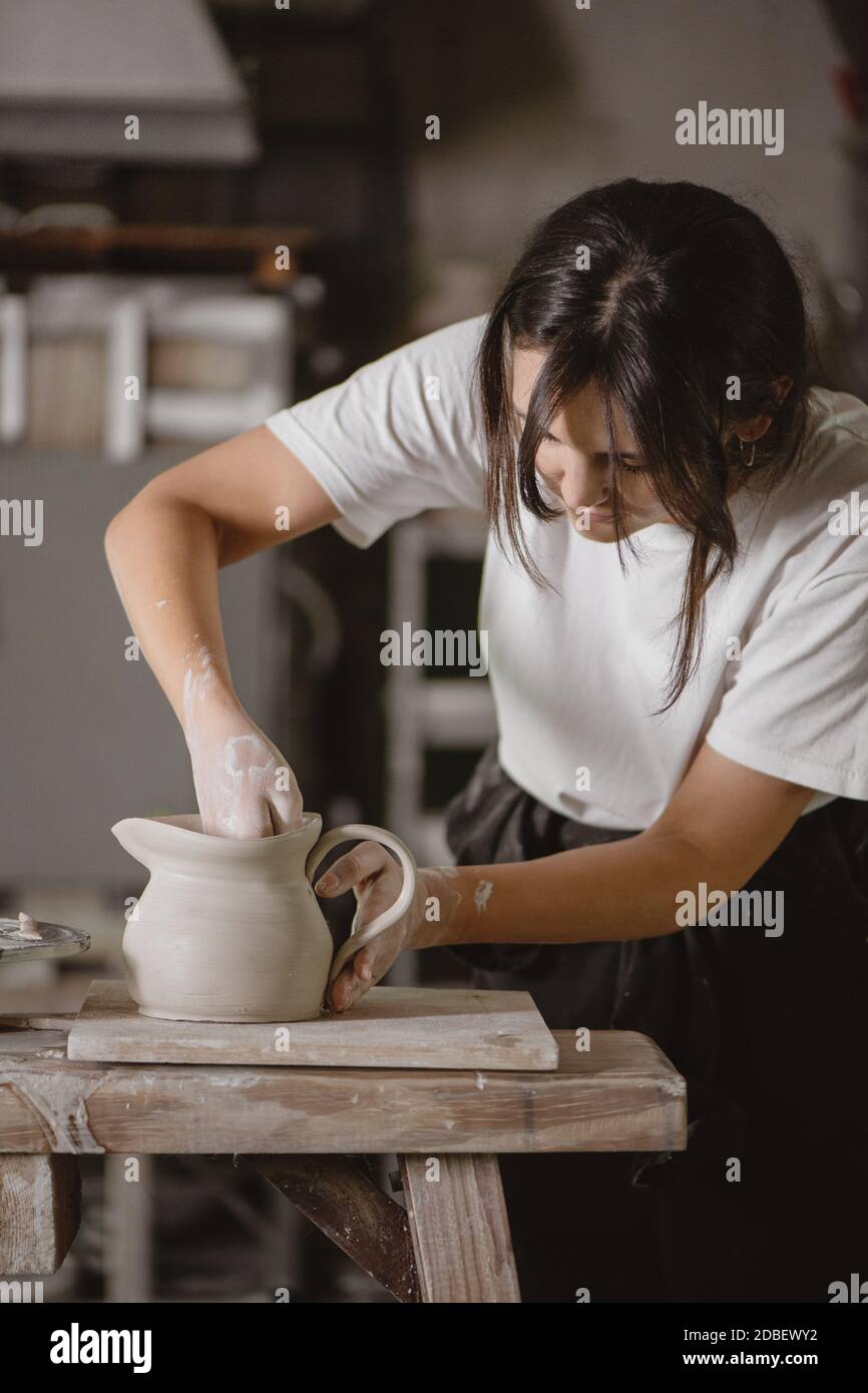 Femmina vasaio che fa una caraffa di argilla in uno studio. Foto Stock