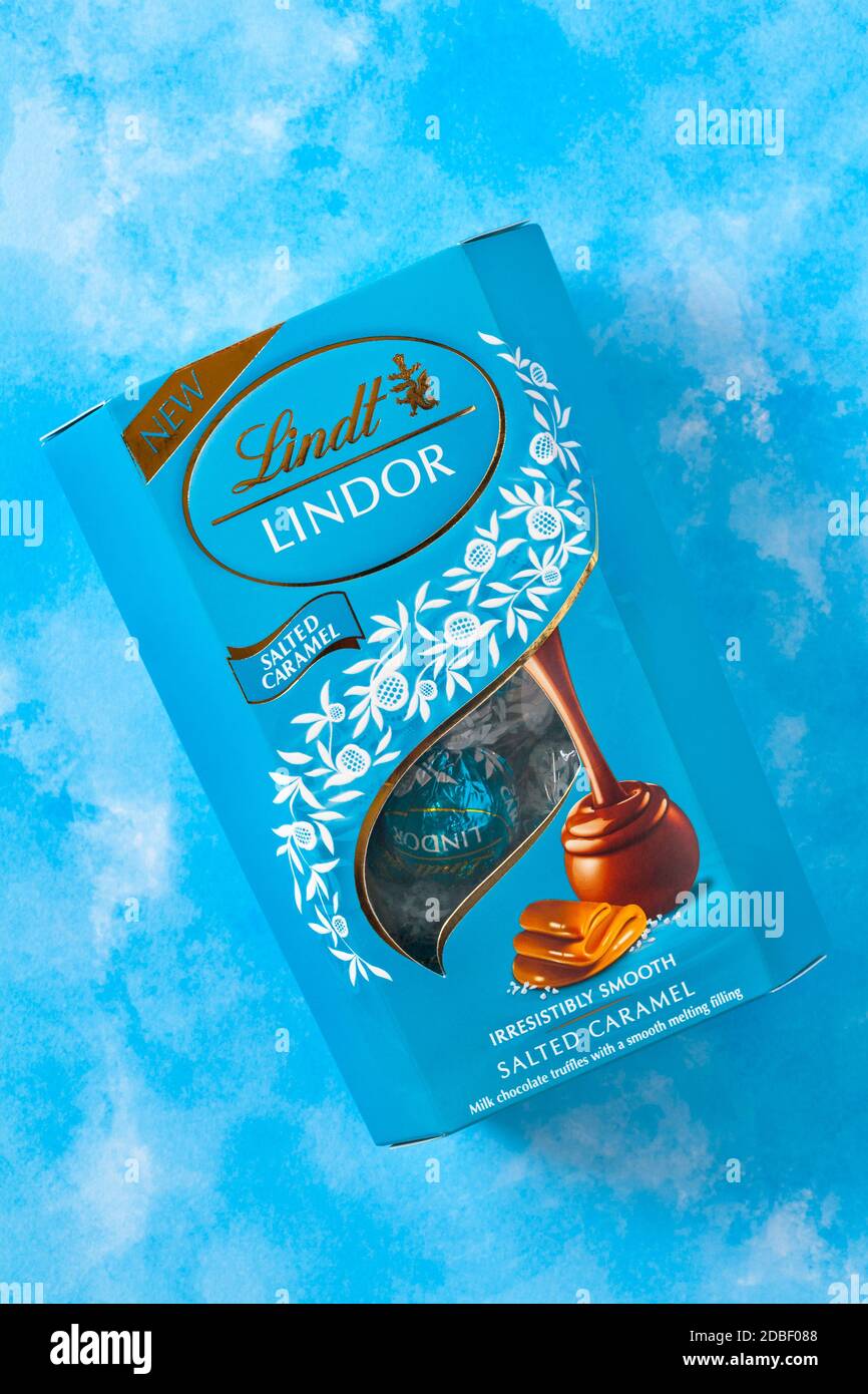 Scatola di Lindt Lindor caramello salato irresistibilmente liscio caramello salato tartufi di cioccolato al latte con un morbido ripieno di fusione sfondo blu Foto Stock