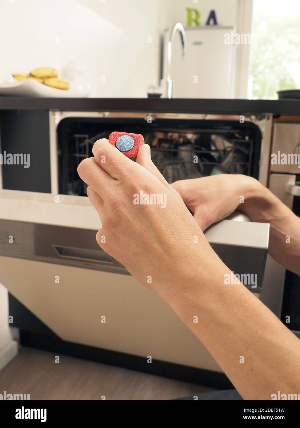 Un uomo di mezza età dota una lavastoviglie di una linguetta di pulizia, concetto di pulizia Foto Stock