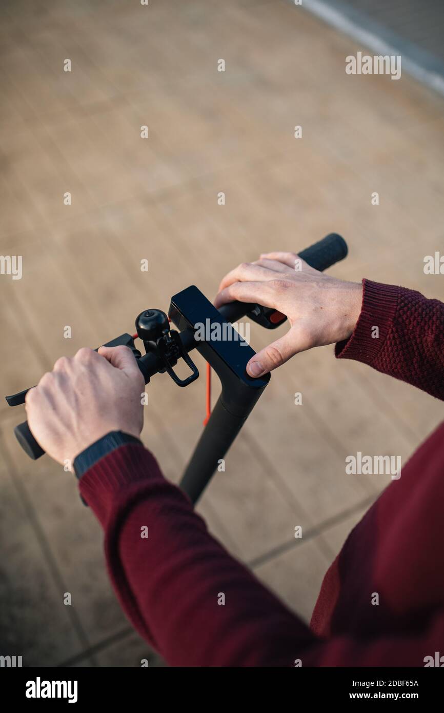 Pattino elettrico con le mani che toccano i pulsanti. Giovane uomo con skate elettrico per muoversi in città. Foto Stock