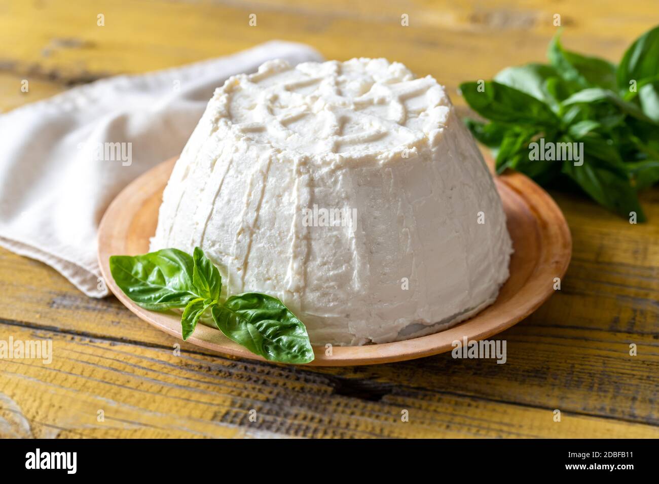 Ricotta un formaggio di siero di latte italiano con foglie di basilico fresco Foto Stock