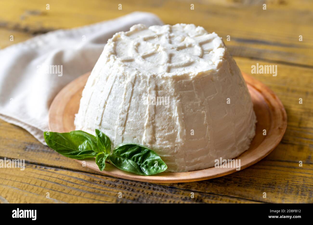 Ricotta un formaggio di siero di latte italiano con foglie di basilico fresco Foto Stock