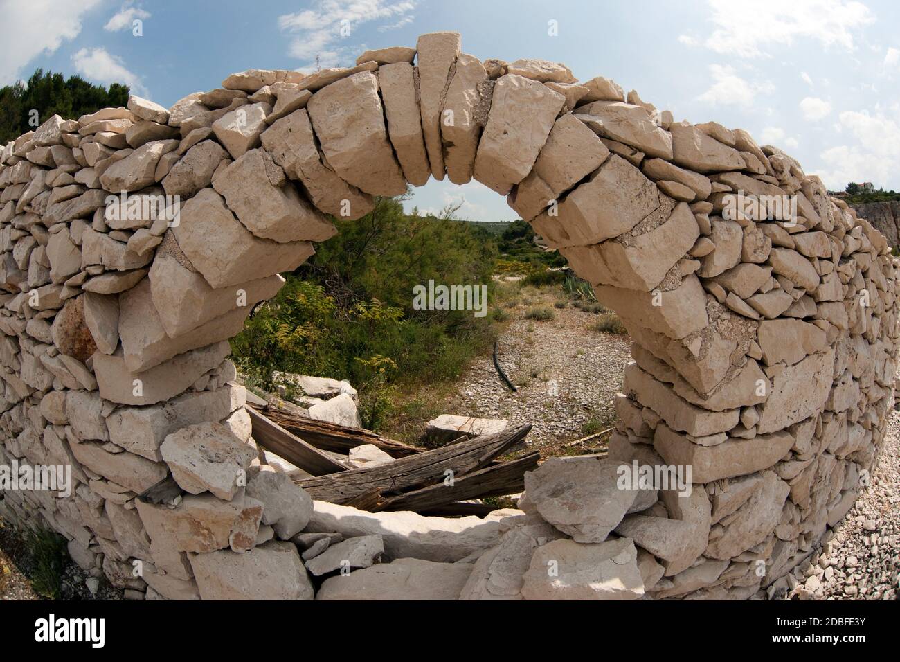 Vista attraverso un'apertura in pietra muro su un percorso in un paesaggio aperto, Croazia Foto Stock