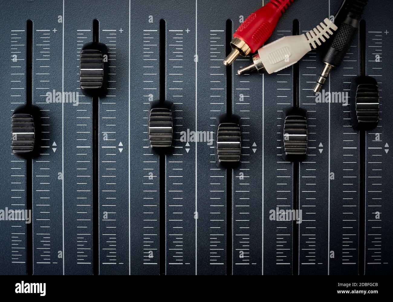 cavi audio con connettori rca sui fader di un mixer per la produzione audio Foto Stock