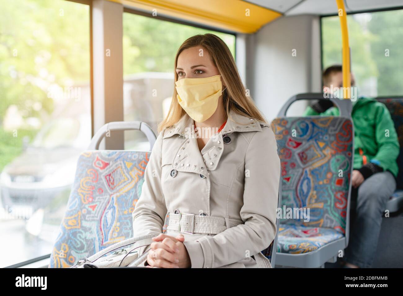 Donna che usa i trasporti pubblici durante la crisi del covid-19 indossando la maschera facciale Foto Stock