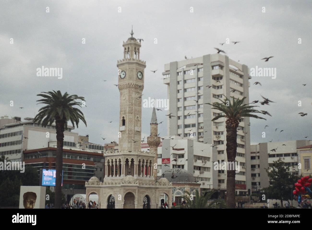 Izmir, Turchia - 16 novembre 2020 Film scan con qualche granello della Torre dell'Orologio di Konak con alcune persone e piccioni volanti. Foto Stock