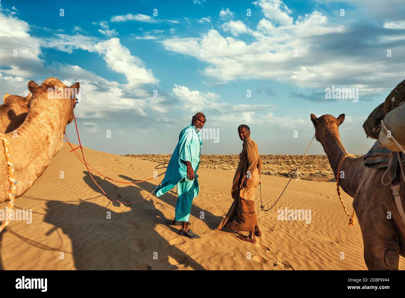Rajasthan viaggio sfondo - due cammelli indiani (camel driver) con cammelli in dune del deserto di Thar. Jaisalmer, Rajasthan, India Foto Stock