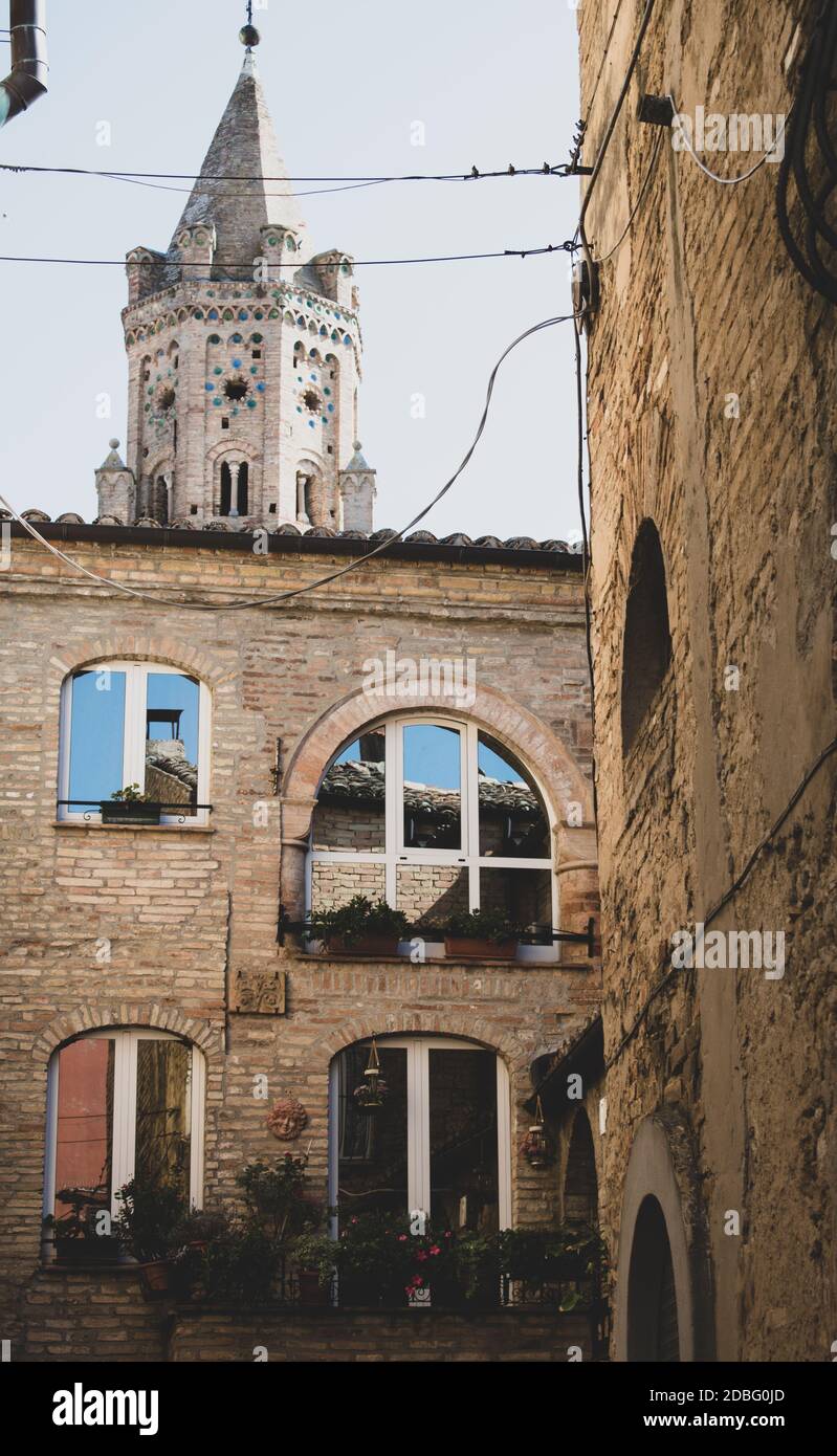 Bandiera italiana bloccata in una ruota di legno contro mattoni e. parete con piante e specchio Foto Stock