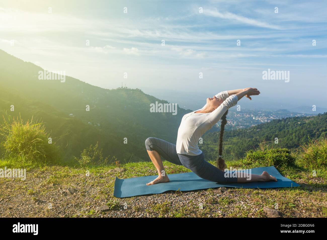 Sport fit donna pratica yoga Anjaneyasana - basso affondo mezzaluna posa all'aperto in montagna al mattino Foto Stock