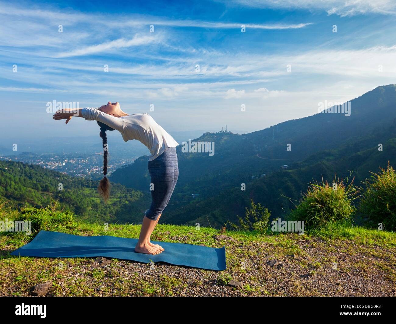 Giovane uomo sportivo che fa yoga Soldi Salutation Surya Namaskar Posa Hasta Utttanasana all'aperto in montagna Foto Stock