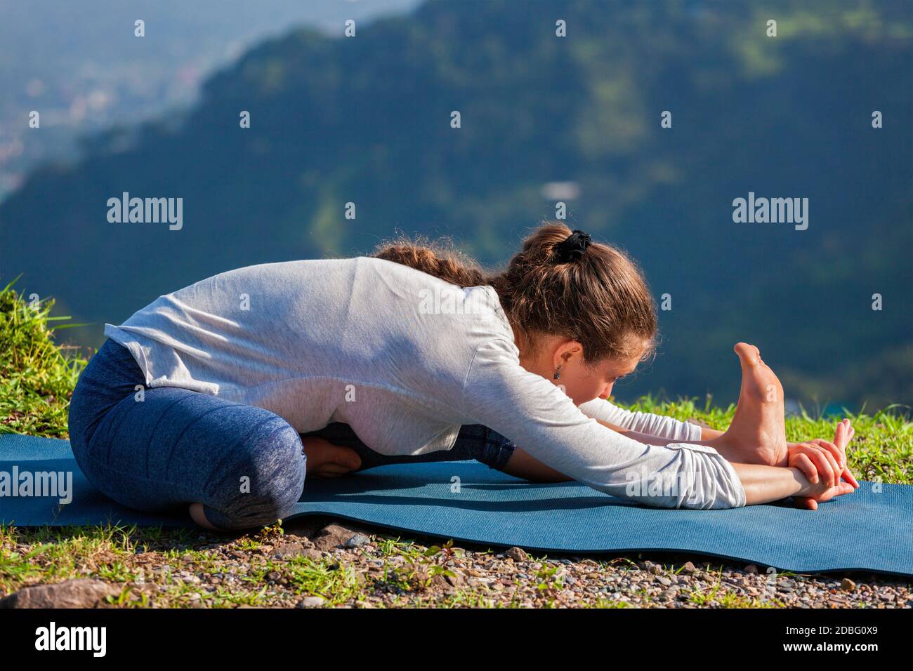 Yoga all'aperto - donna che fa Ashtanga Vinyasa yoga Janu Sirsasana Una testa al ginocchio che si estende in posizione asana all'aperto Foto Stock