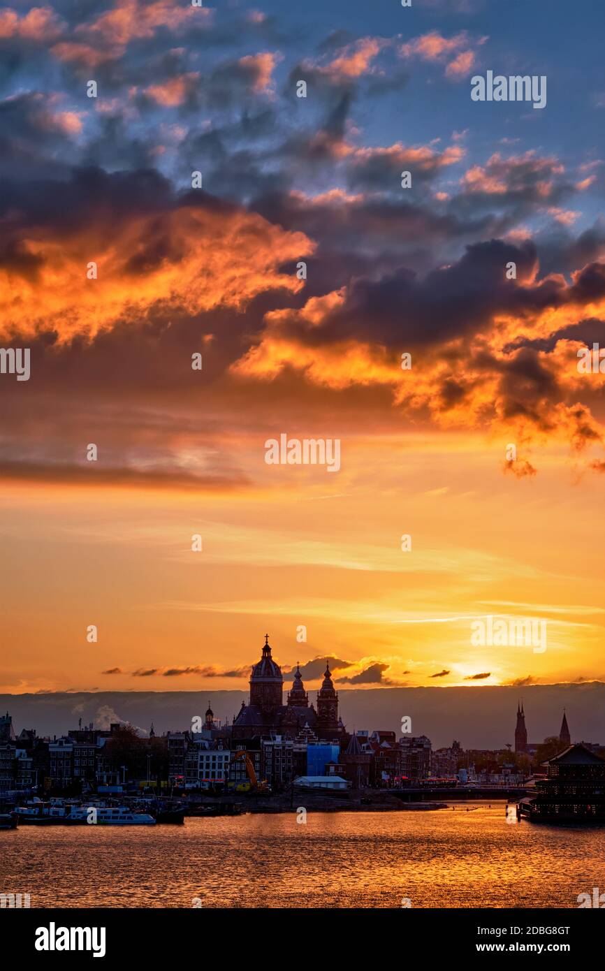Lo skyline della città di Amsterdam con la Chiesa di San Nicola (Sint-Nicolaaskerk) al tramonto con il cielo drammatico. Amsterdam, Paesi Bassi Foto Stock