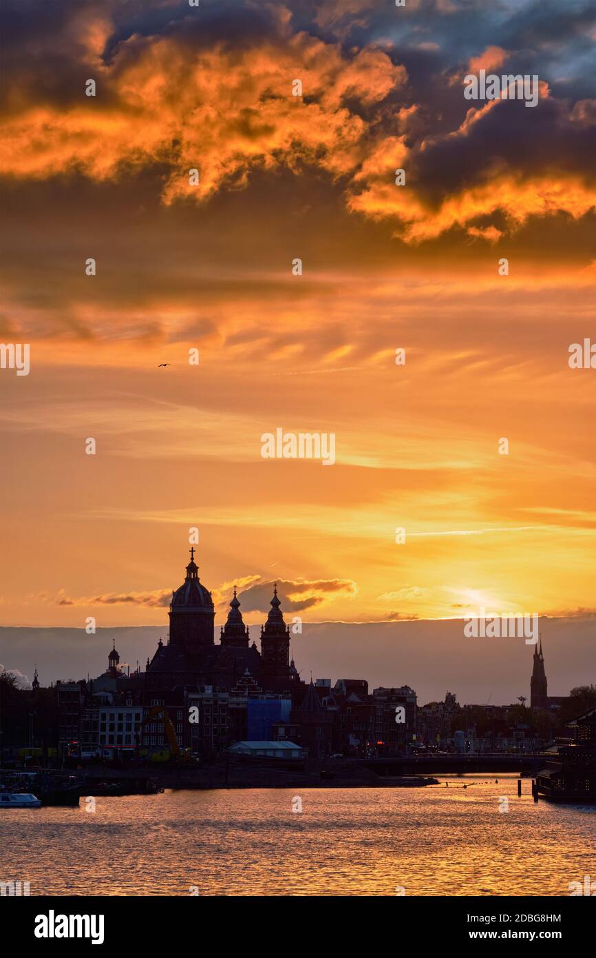 Lo skyline della città di Amsterdam con la Chiesa di San Nicola (Sint-Nicolaaskerk) al tramonto con il cielo drammatico. Amsterdam, Paesi Bassi Foto Stock