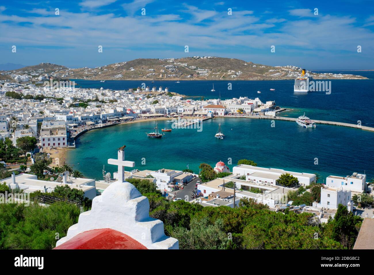 Vista della città di Mykonos meta turistica turistica turistica turistica di vacanza con famosi mulini a vento, e porto con barche e yacht con la chiesa di San Basilio croce in th Foto Stock