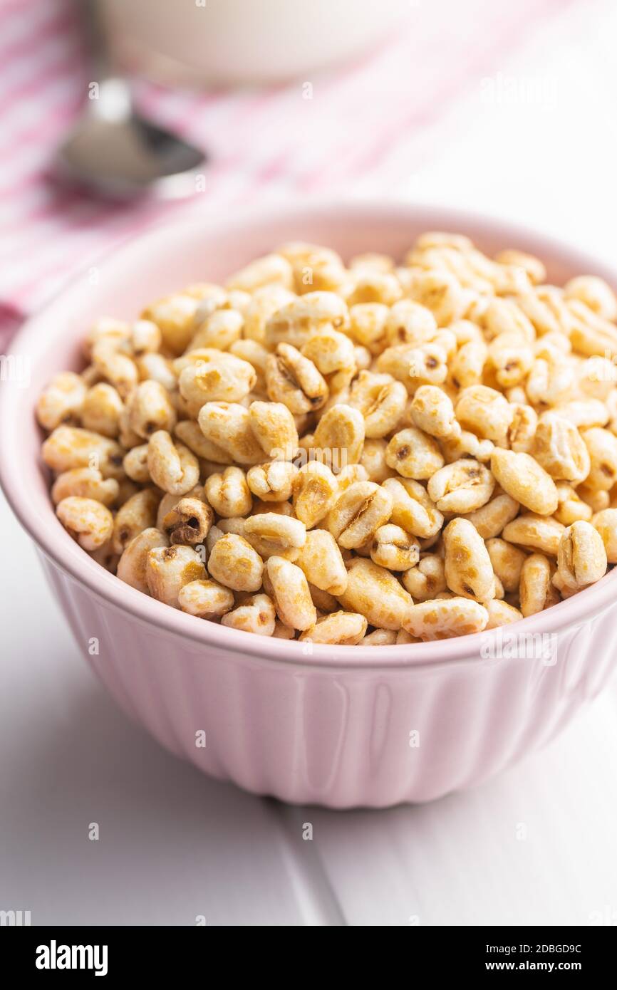 Grano soffiato coperto di miele in ciotola su tavola bianca. Foto Stock