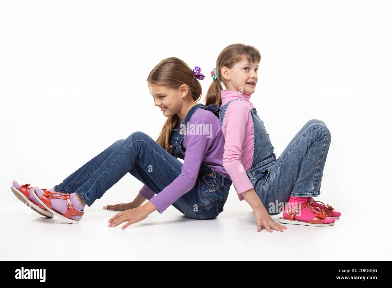 I bambini seduti sul pavimento che spingono le spalle Foto Stock