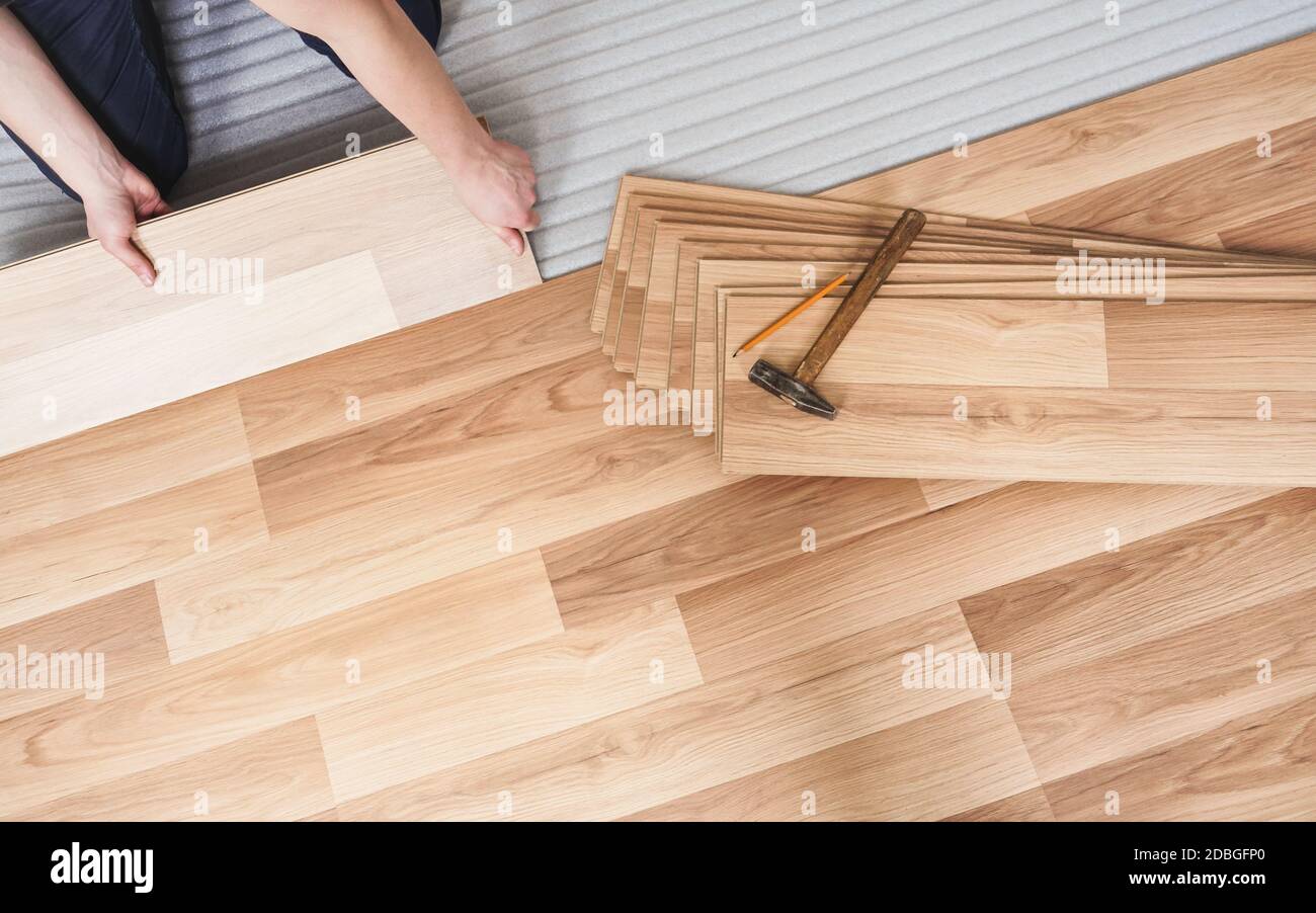 Installazione del pavimento laminato, dettaglio sulle mani dell'uomo che  reggono la piastrella di legno, sopra lo strato di base di schiuma bianco  Foto stock - Alamy