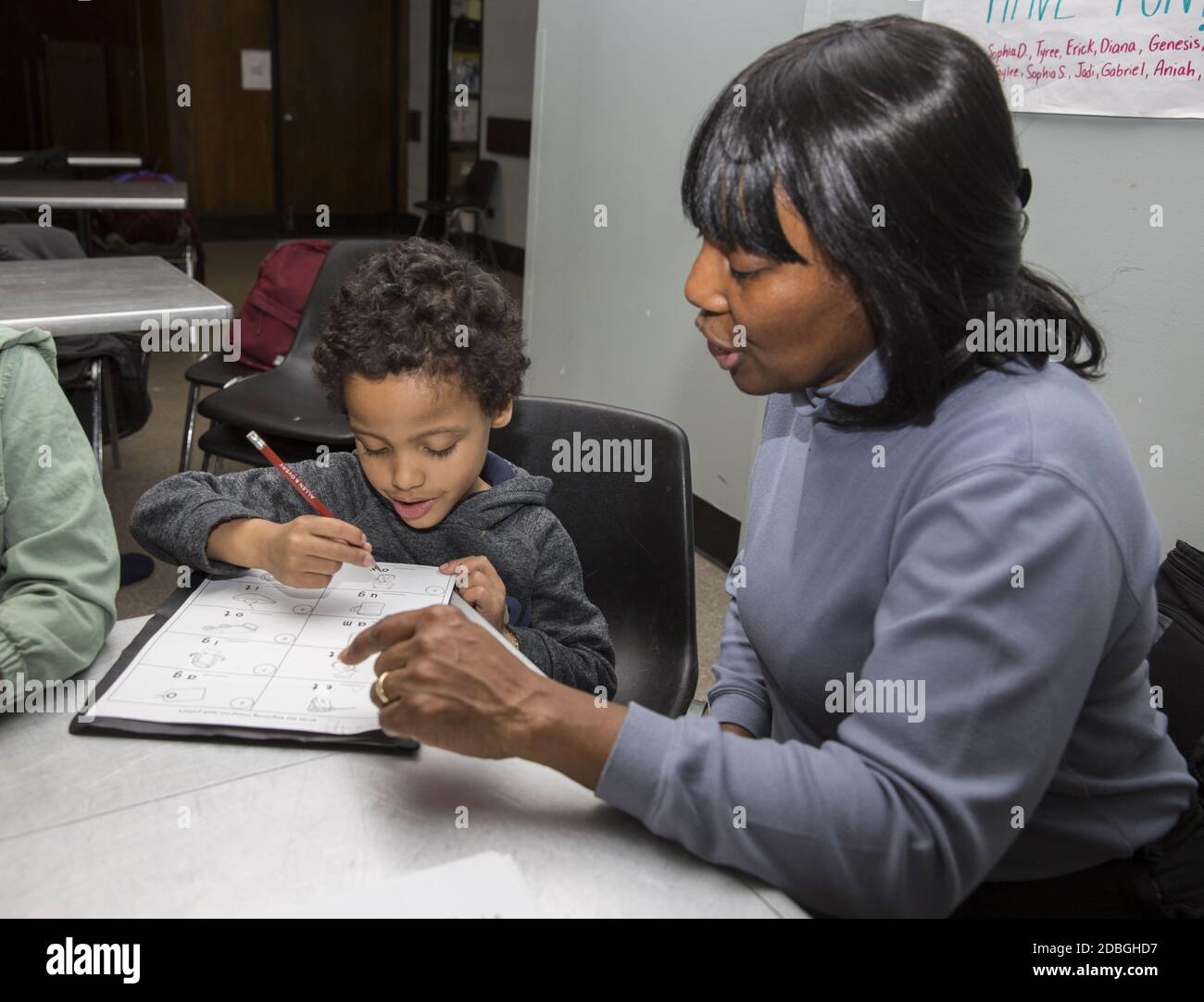 L'insegnante aiuta gli studenti delle scuole elementari a lavorare sull'ortografia delle parole in un programma post-scolastico presso un centro di Manhattan, New York City. Foto Stock