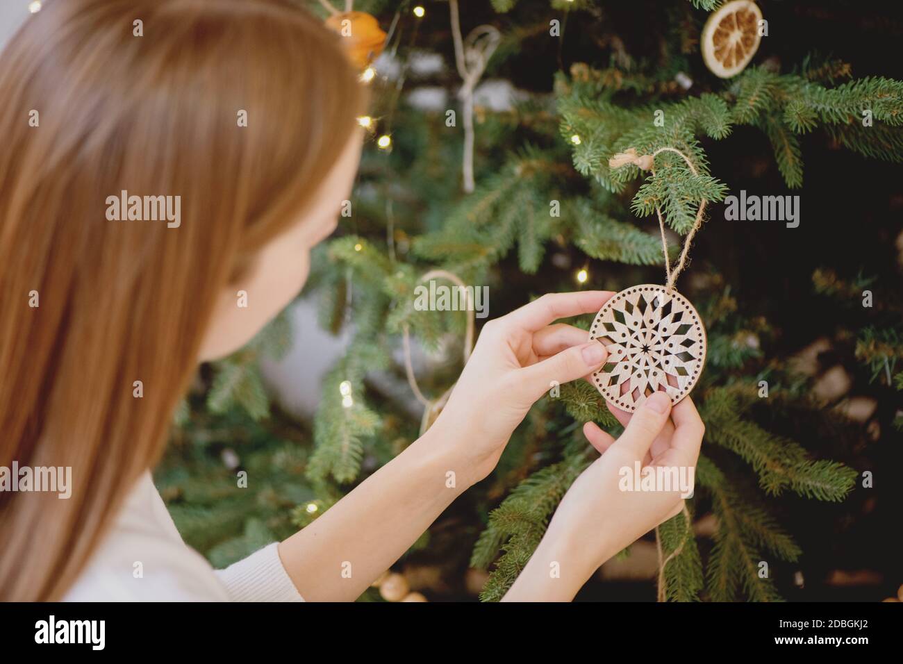 Primo piano di donna che decorano l'albero di natale con giocattolo di Natale mestiere. Concetto di vacanza invernale. Foto Stock