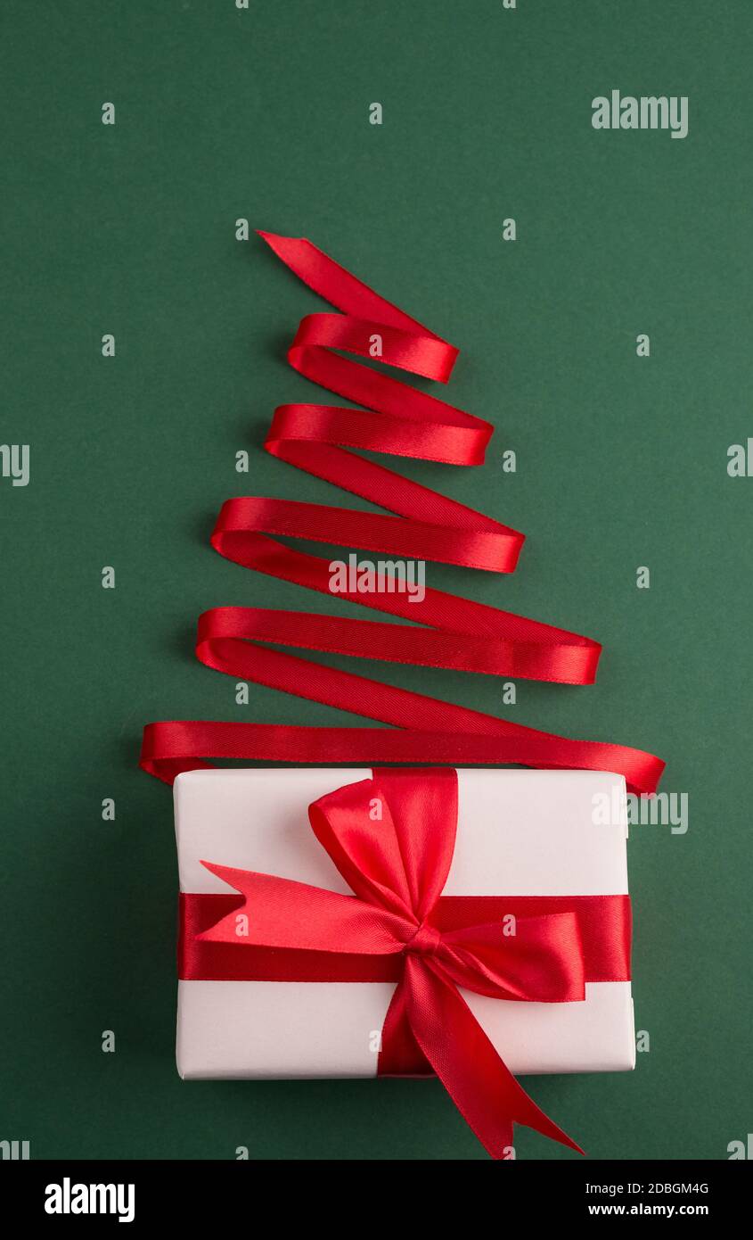 Albero di Natale fatto di nastro rosso seta e scatola regalo su uno sfondo  verde luminoso. Buon Natale e felice Capodanno sfondo festivo con vuoto spa  Foto stock - Alamy