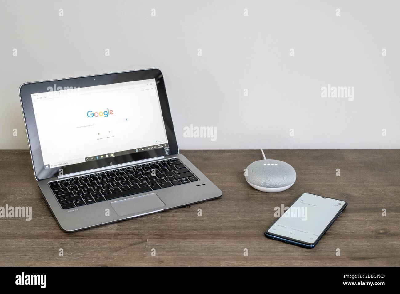 Adelaide, Australia - 7 luglio 2019: Google Home Mini con computer portatile HP con Windows 10 e telefono cellulare impostato sul tavolo accanto l'uno all'altro Foto Stock