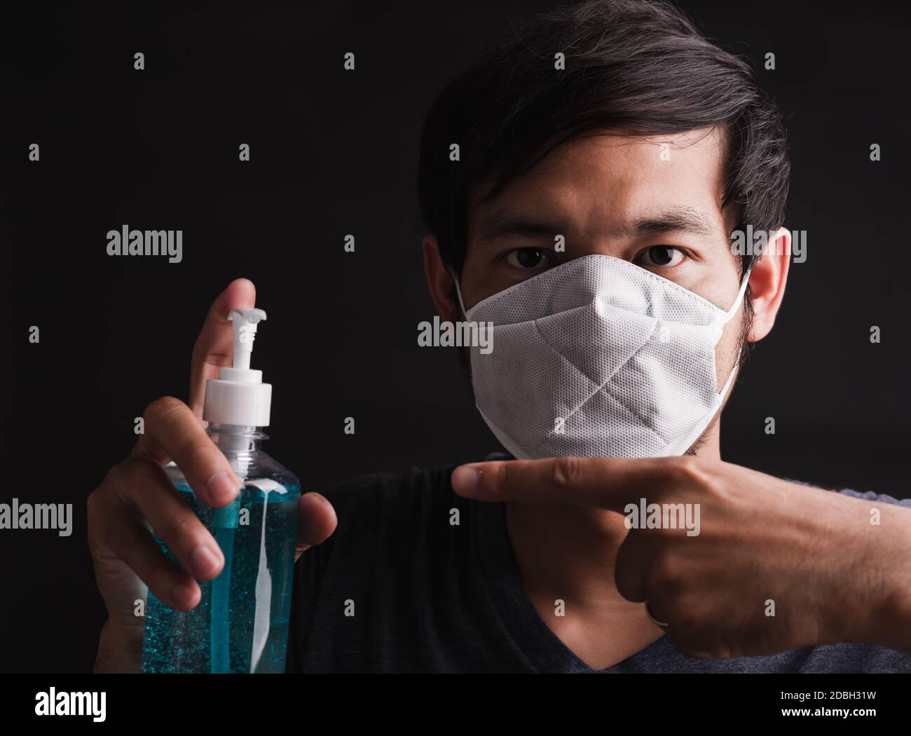 Closeup asiatico bell'uomo che indossa maschera protettiva viso con paura di tenere gli occhi e gel disinfettante punto, prevenzione igiene COVID-19 virus o coronav Foto Stock