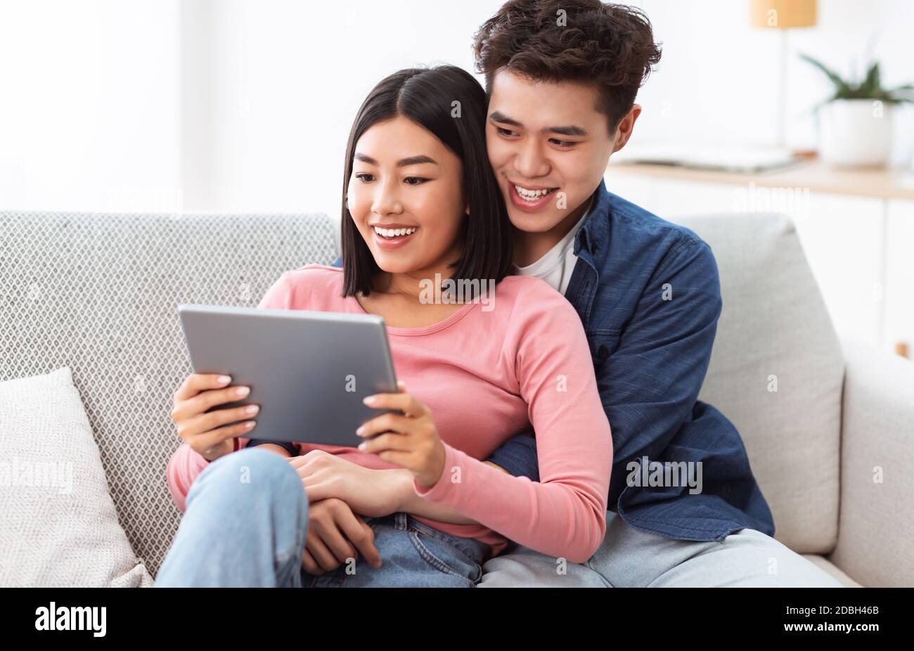 I coniugi giapponesi che guardano il film preferito in linea seduto sul divano interno Foto Stock