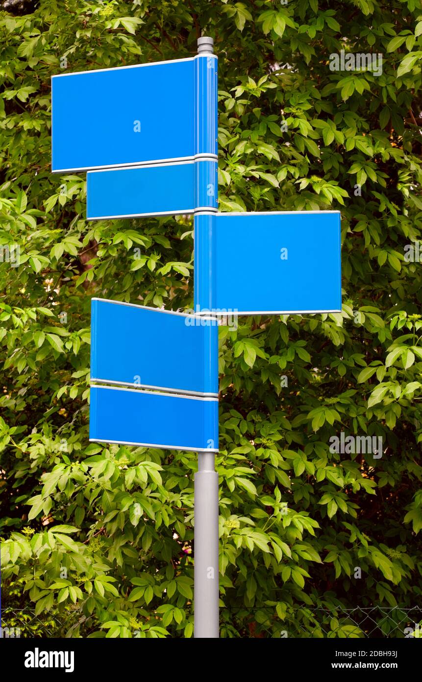 Blank cartelli stradali in colore blu con un foglie verdi sullo sfondo Foto Stock