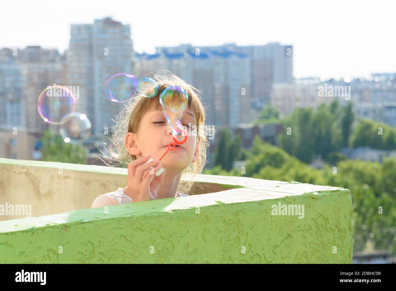Un bambino si diverte sul balcone di un edificio a più piani che soffia bolle  di sapone Foto stock - Alamy