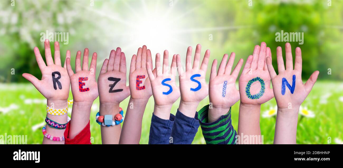 Bambini mani costruire colorato tedesco parola Rezession significa recessione. Prato verde soleggiato come sfondo Foto Stock