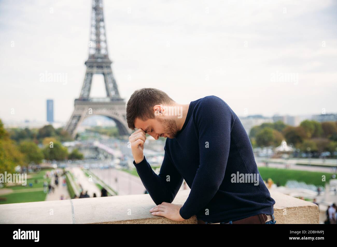 Bell'uomo che indossa un pullover blu scuro è in piedi Lo sfondo della Torre Eiffel Foto Stock