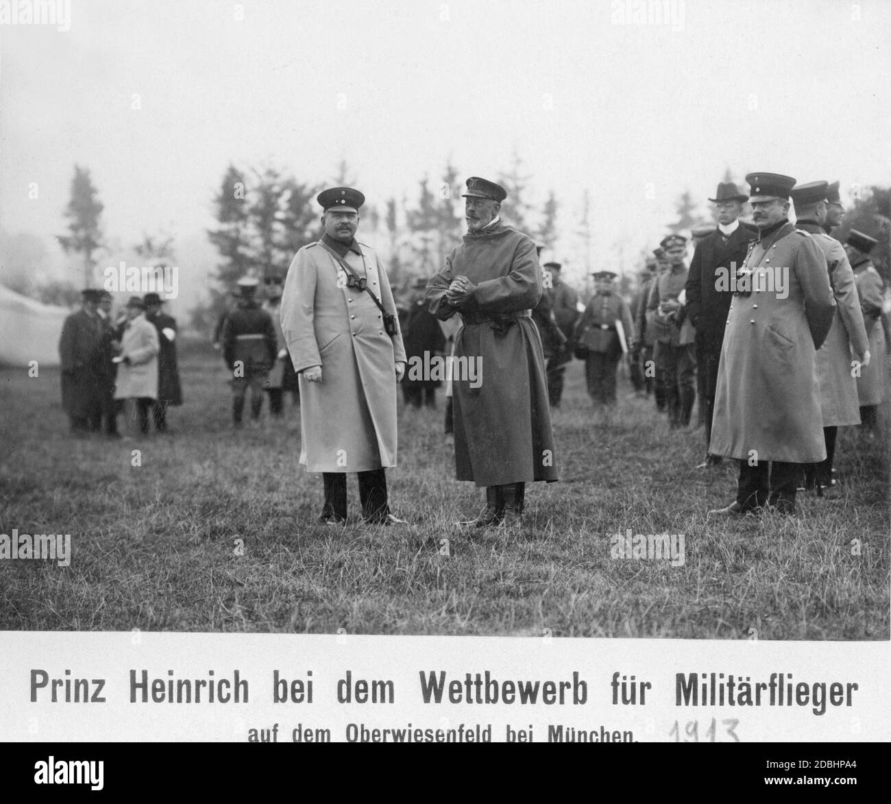 Il principe Enrico di Prussia (al centro della foto, in un cappotto scuro) si trova in piedi insieme ad altri ufficiali dell'aeroporto di Oberwiesenfeld, vicino a Monaco. Una gara per piloti militari si è tenuta lì nel 1913. Foto Stock