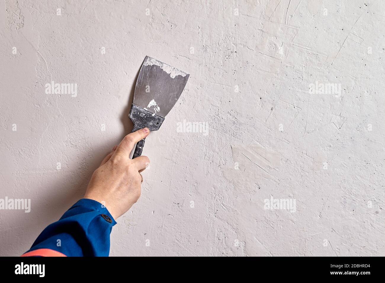Il pittore domestico sta patching le fessure più piccole e buchi preme il composto di spackling attraverso le imperfezioni della superficie con un coltello di stucco, assicurandosi che spackle Foto Stock