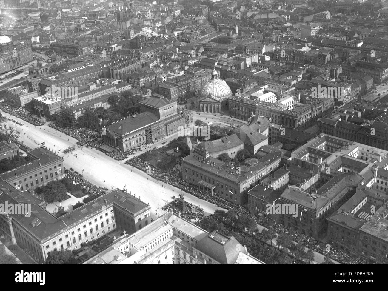 La fotografia aerea del 1926 mostra il viale Unter den Linden con la Neue Wache, l'Università Humboldt e la Biblioteca di Stato di Berlino-Mitte. Si sta svolgendo una sfilata e molte persone la stanno guardando. Al centro della foto si trova la Cattedrale di Sant'Edvige a Bebelplatz e l'Opera di Stato. Foto Stock