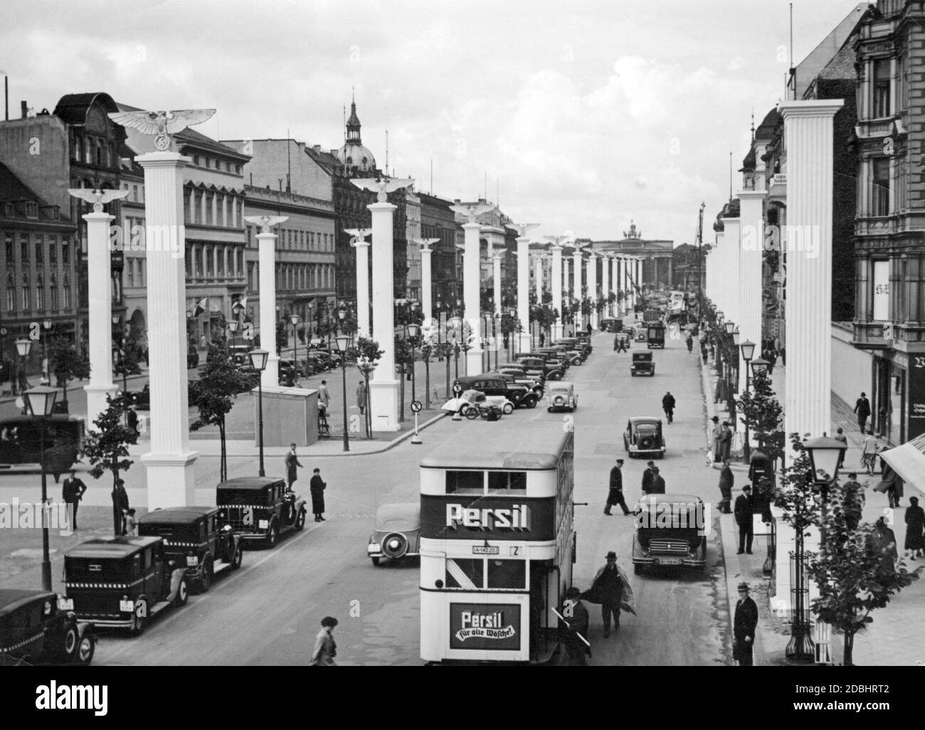 "Benito Mussolini ha visitato la Germania tra il 25 e il 29 settembre 1937. L'immagine mostra la strada Unter den Linden a Berlino, decorata con bandiere e simboli nazisti per la visita. Un autobus a due piani ferma davanti all'hotel per prendere i passeggeri. Pubblicità per il marchio ''Persil - fuer alle Waesche''. Sullo sfondo c'è la porta di Brandeburgo." Foto Stock