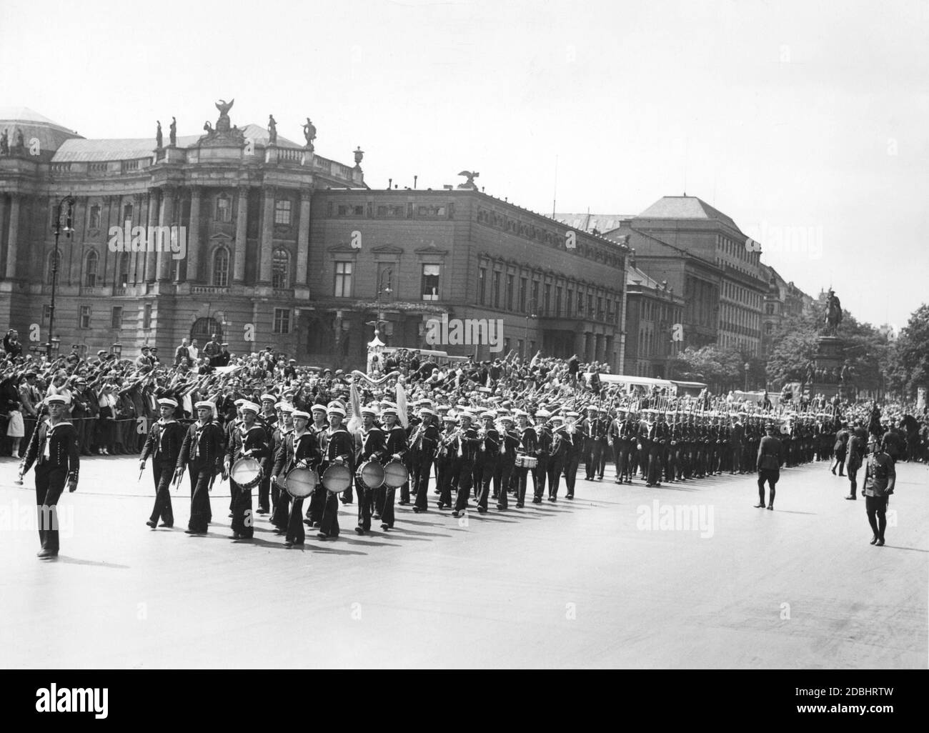 Una banda di marching del Reichsmarine, seguita da molti altri marinai, attraversa la strada Unter den Linden a Berlino nel 1933. La gente al lato della strada esegue il saluto nazista. Sullo sfondo si trovano l'Alte Bibliothek (a sinistra), l'Alte Palais (a destra) e la statua equestre di Federico il Grande (a destra). Foto Stock