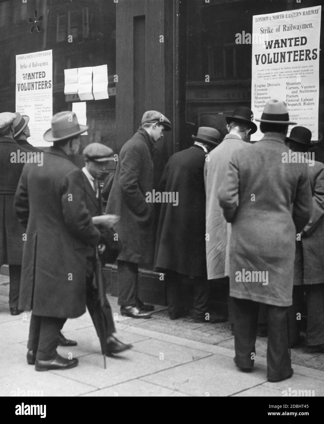 Passers-by stand di fronte a manifesti che reclutano lavoratori volontari per la ferrovia come sciopero durante lo sciopero generale di Londra. Foto Stock