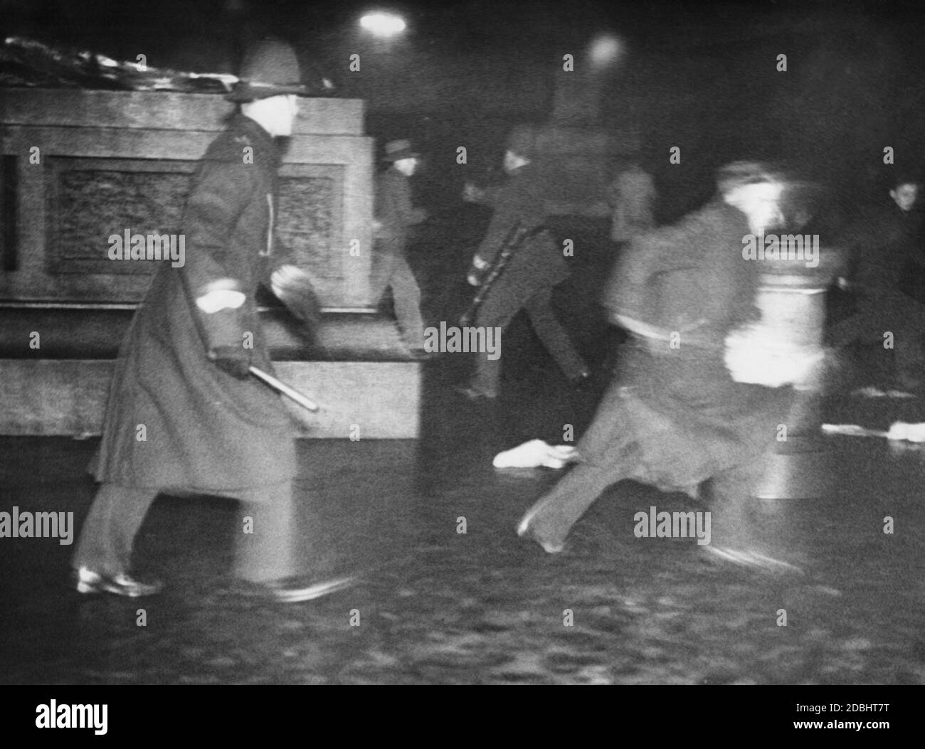 Un poliziotto persegue i dimostranti di notte in Trafalgar Square di Londra. Foto Stock