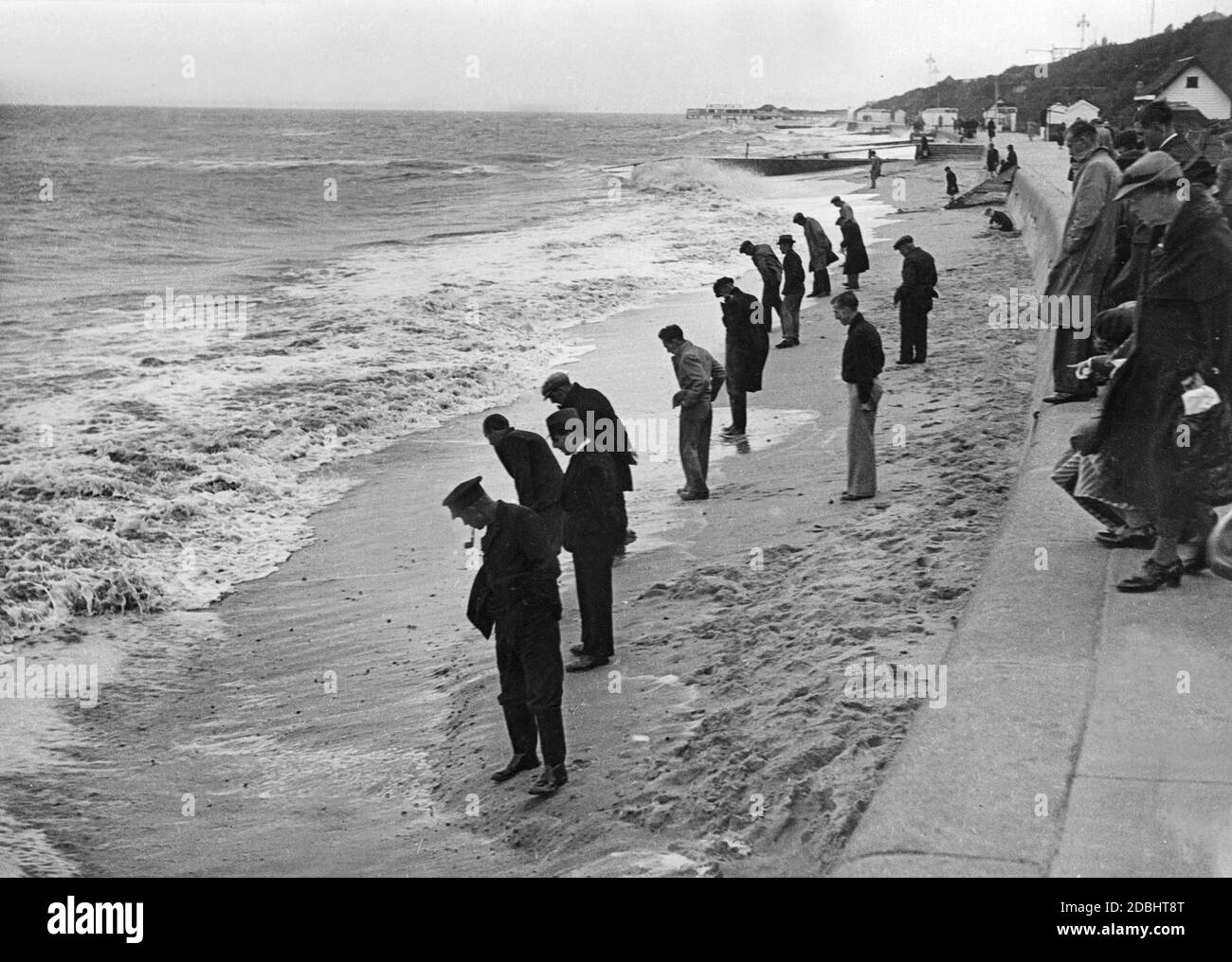 Dopo le prime tempeste autunnali, i beachcomber cercano le spiagge vicino a Clacton nella contea di Essex. Foto Stock