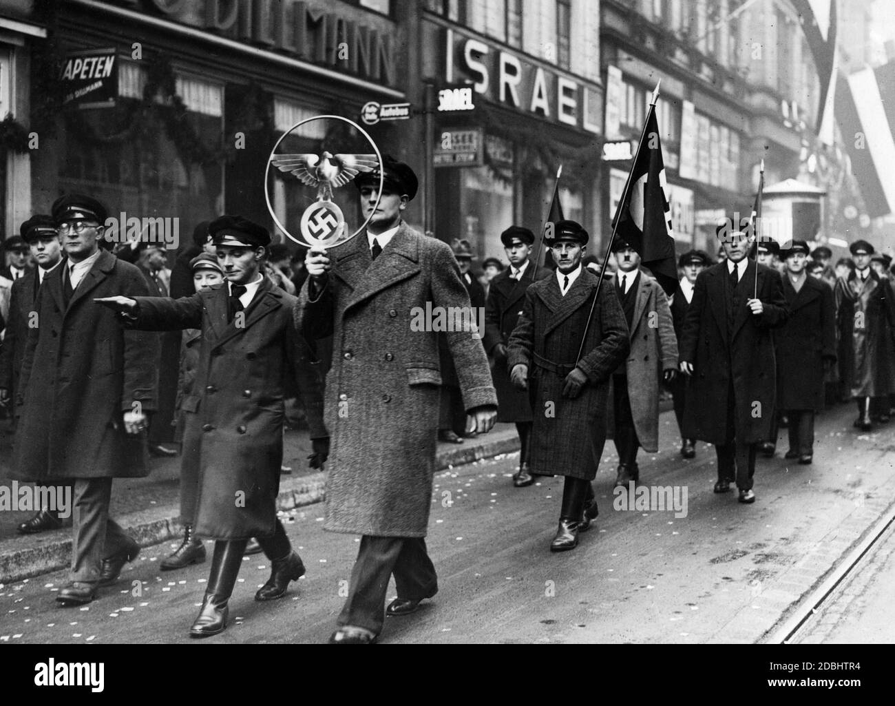 Dopo il referendum sull'annessione della Saarland al Reich tedesco, gli uomini marciano per le strade di Saarbruecken con bandiere swastika e simboli sovrani del Reich. Foto Stock