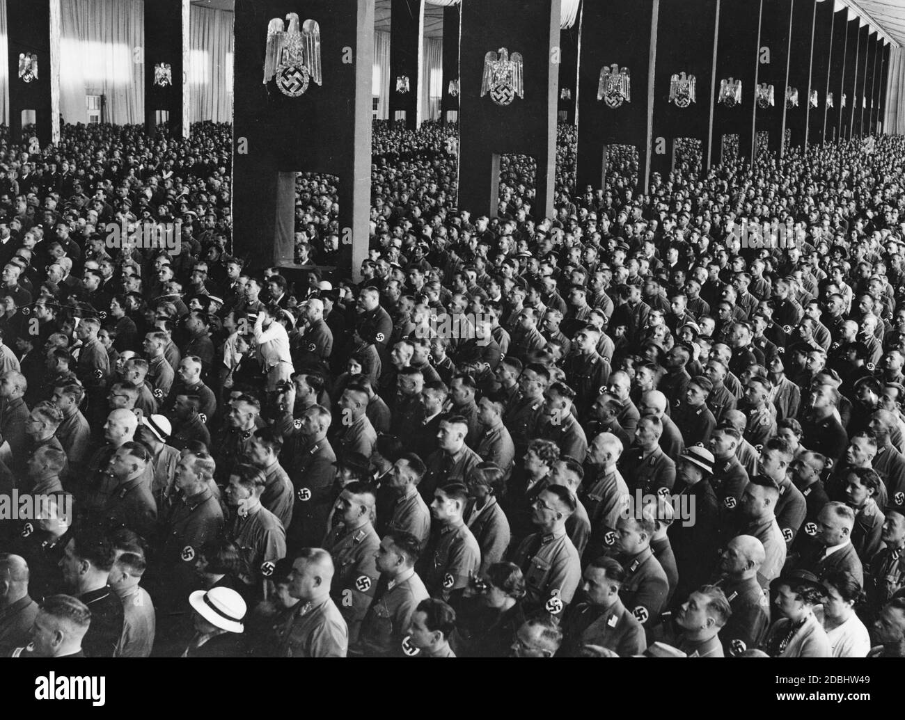 Vista dei partecipanti riuniti all'evento di apertura del Congresso del Partito nazista a Luitpoldhalle di Norimberga. Le colonne sono decorate con i simboli della sovranità nazista. Foto Stock