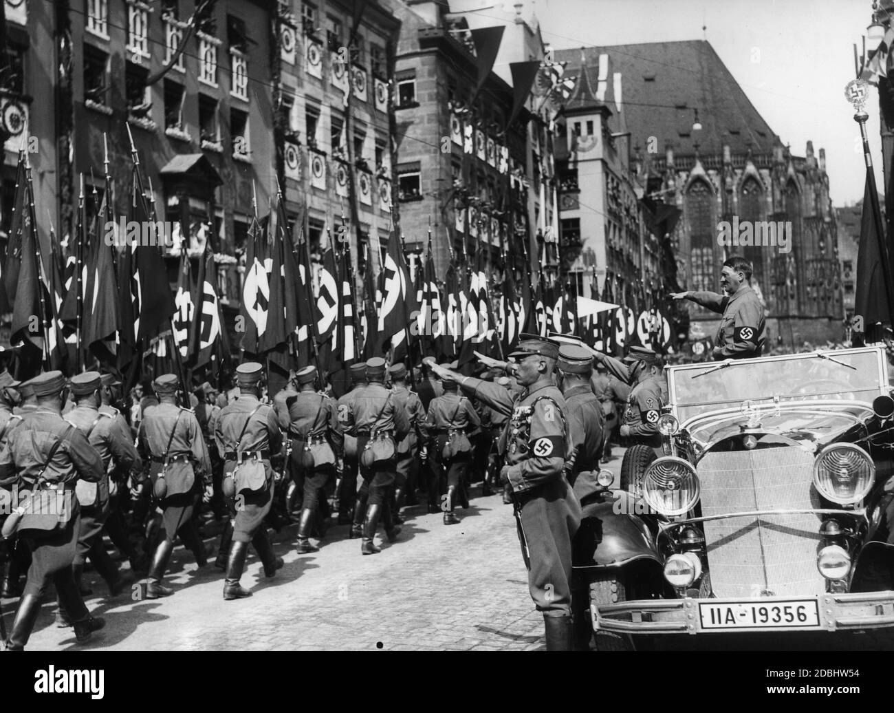 Adolf Hitler, in piedi nella sua Mercedes, prende il saluto dei portatori di bandiera SA mentre marciano oltre sulla piazza principale del mercato di Norimberga, la cosiddetta Adolf-Hitler-Platz. Davanti a lui sulla sinistra c'è Franz Pfeffer von Salomon, sulla destra Viktor Lutze. Sullo sfondo, una parte della Chiesa del Sebaldo. Foto Stock