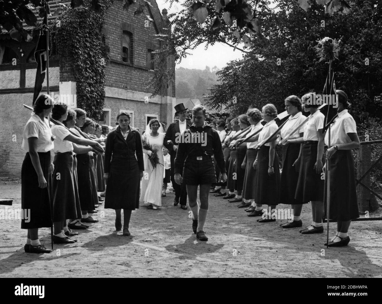 La sposa e lo sposo, che stanno servendo nel Freiwilliger Arbeitsdienst ('Servizio volontario del lavoro', FAD), sono ricevuti da una guardia d'onore di fronte alla chiesa. Foto Stock