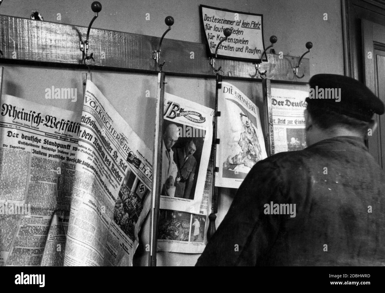 'Oltre ai libri, la sala lettura offre anche gli ultimi giornali e riviste. Sopra i ganci del giornale c'è un segno che dice: ''la sala di lettura non è un posto per parlare forte, per giocare le carte, per litigare e scuffling''. Qui di seguito sono riportati i giornali, tra gli altri: Rheinisch-Westfaelische Zeitung, Voelkischer Beobachter, Illustrierter Beobachter, (foto di copertina: Adolf Hitler con Paul Ludwig Troost) e Die Brenessel." Foto Stock