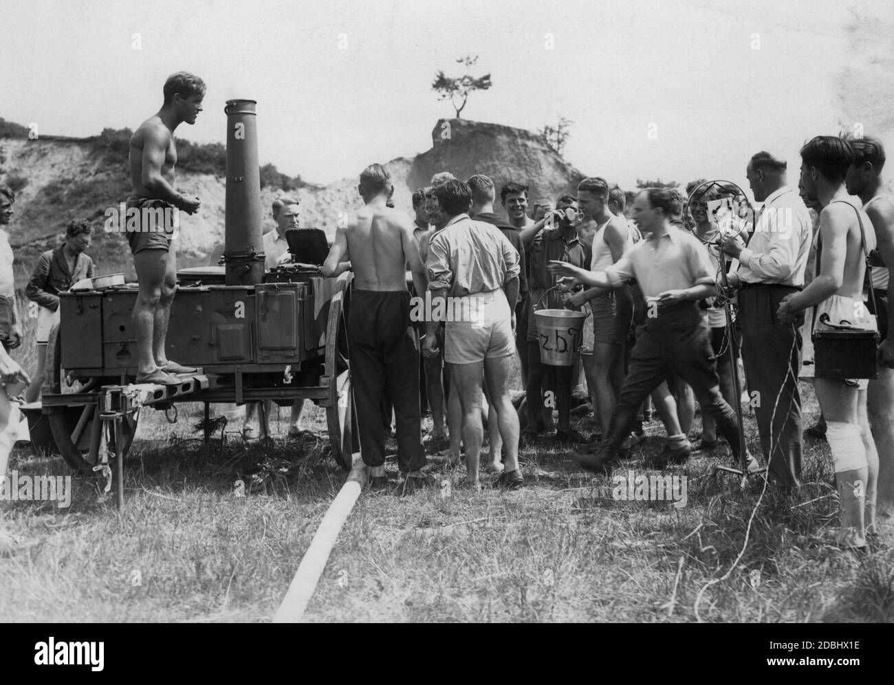 Distribuzione di cibo dalla cucina da campo in secchi in un campo leader della Studentenarbeitsdienst nei pressi di Sperenberg nell'estate del 1933. A destra c'è un giornalista radiofonico che fornisce una relazione. Foto Stock