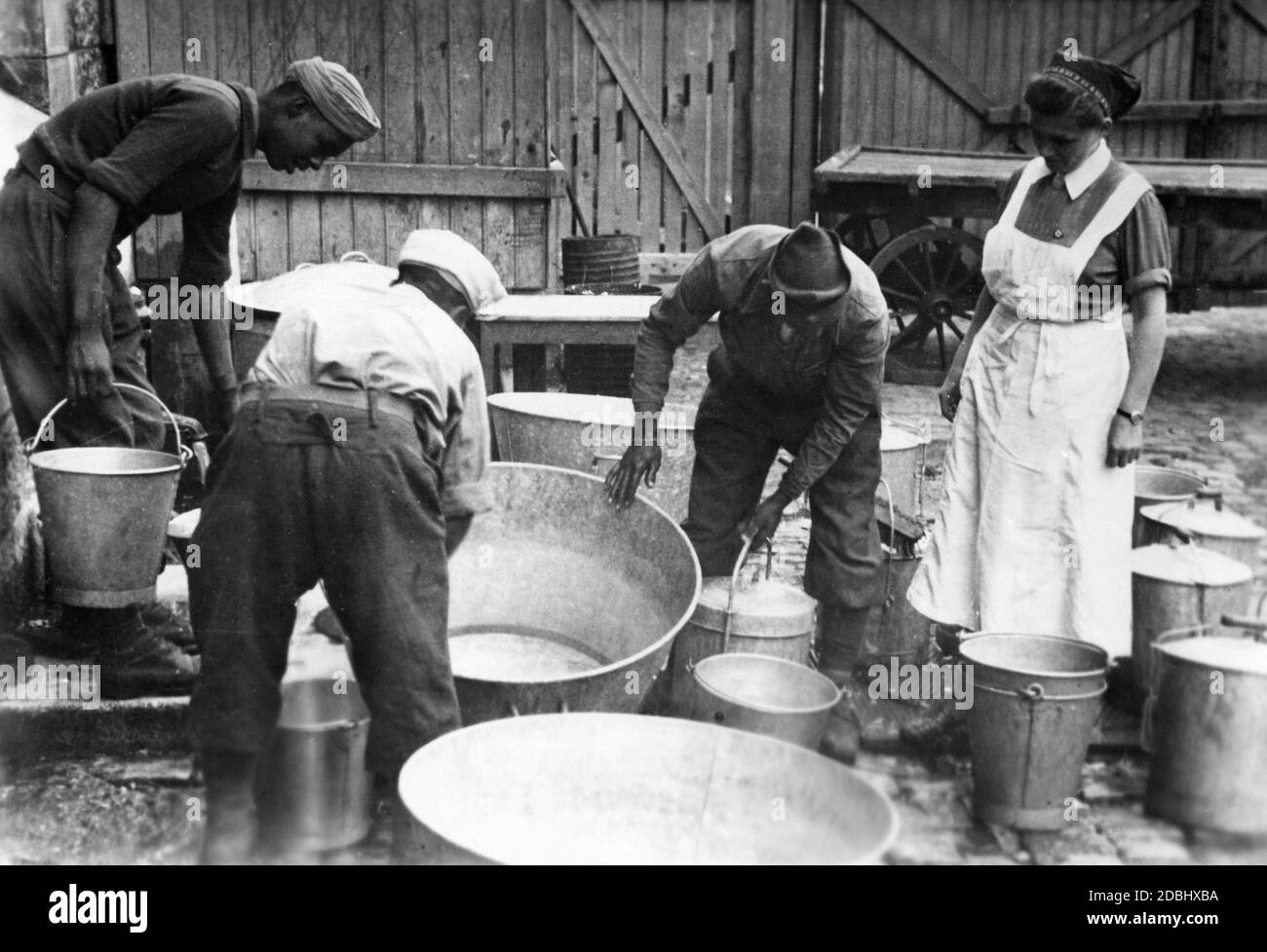 I prigionieri provenienti dal Marocco sono utilizzati per il lavoro forzato. Un volontario della NSV (National Socialist People's Welfare Organization) si trova accanto a loro e osserva il lavoro. Foto Stock