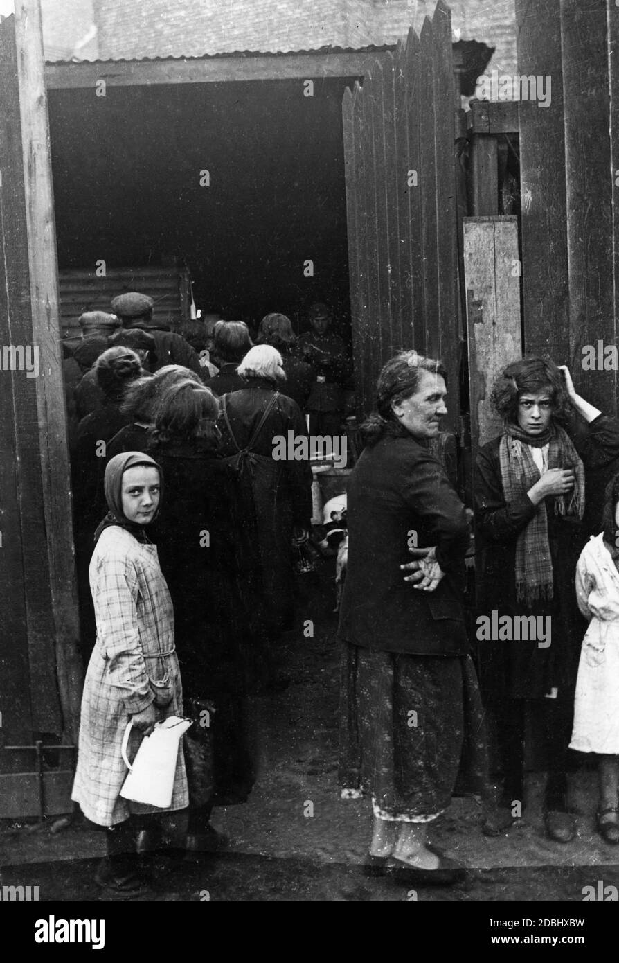 In un edificio, le persone della popolazione civile si allineano presumibilmente per il cibo. Una ragazza con un latte può guardare nella fotocamera. Foto Stock