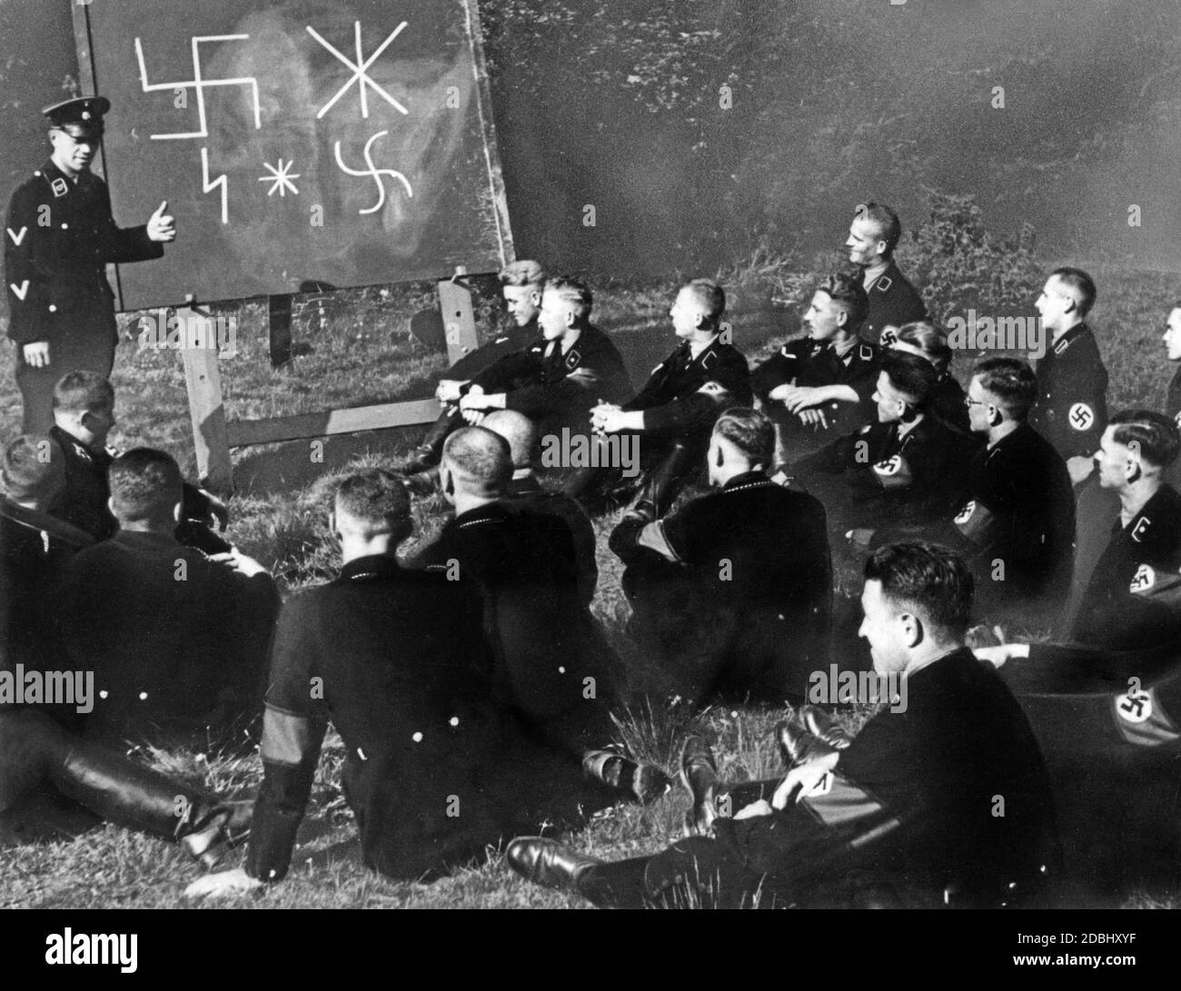 I membri delle SS imparano a conoscere i personaggi runici germanici. Qui l'insegnante mostra ai suoi studenti l'origine della swastika come simbolo della visione del mondo nazionalsocialista. Tutti i presenti indossano un bracciale Swastika. Foto non datata, circa 1935. Foto Stock